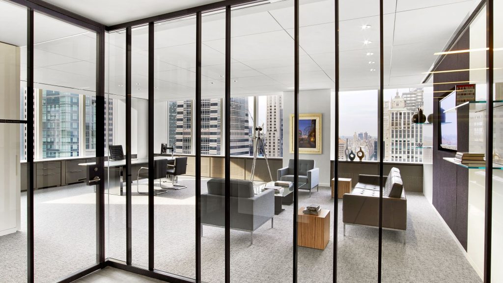 Modern office interior featuring Ultralight demountable glass partitions with a bespoke dark blue anodized aluminum finish.